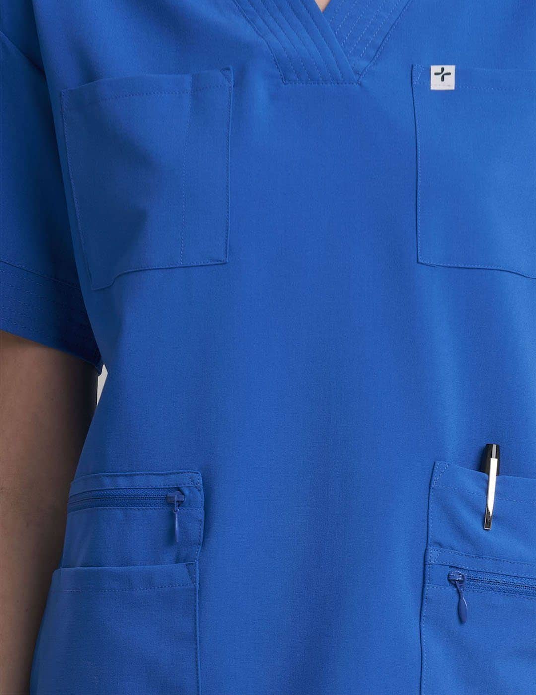 Functional women's V-neck scrub top in royal blue, designed with eight pockets for organized storage. Model is wearing size X-Small